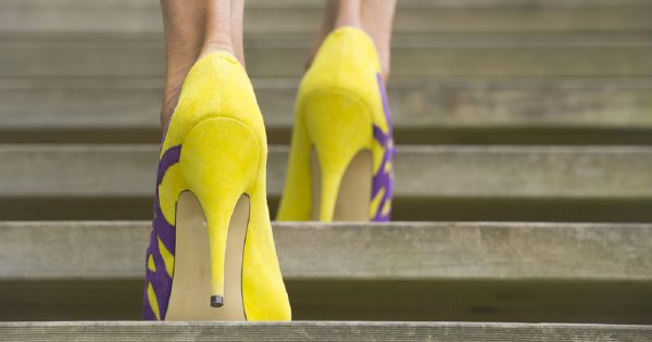 Detail image of woman's legs in high heel shoes walking up stairs outdoor, with blurred background and copy space.